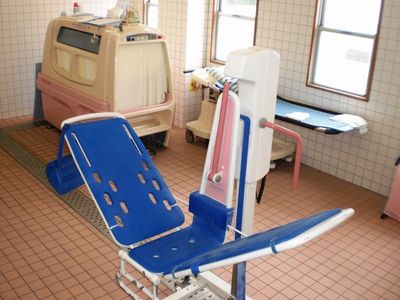 介護施設の浴室。入浴補助用のリフト機器と脱衣所が見える。