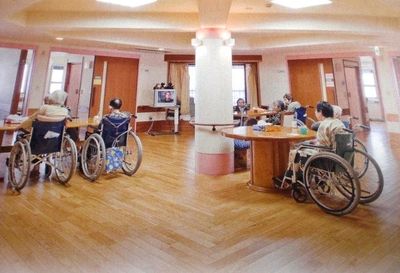 車椅子利用者が集う共用の広間。木張り床、明るい採光で居心地の良い空間設計